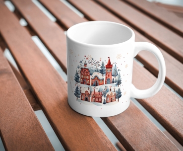 Weiße Keramiktasse mit einem charmanten Winterdorf-Motiv, elegant auf einem Holztisch präsentiert, ideal für gemütliche Momente während der Weihnachtszeit.